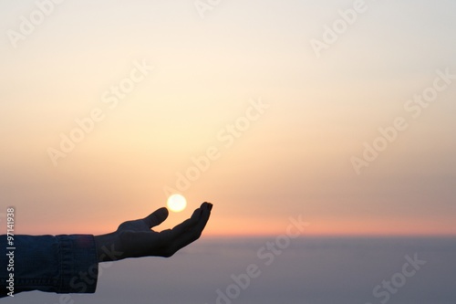 silhouette and hand holding the sun