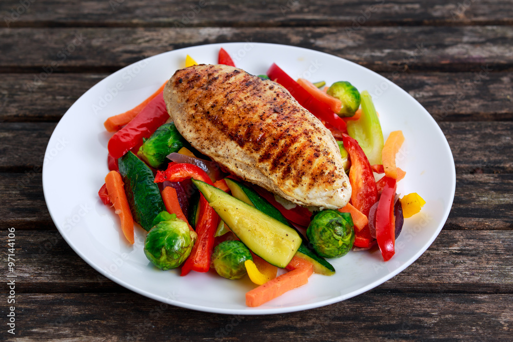 Grilled chicken fillet, breast with cooked vegetable on plates Grilled chicken fillet, breast with cooked vegetable on plates
