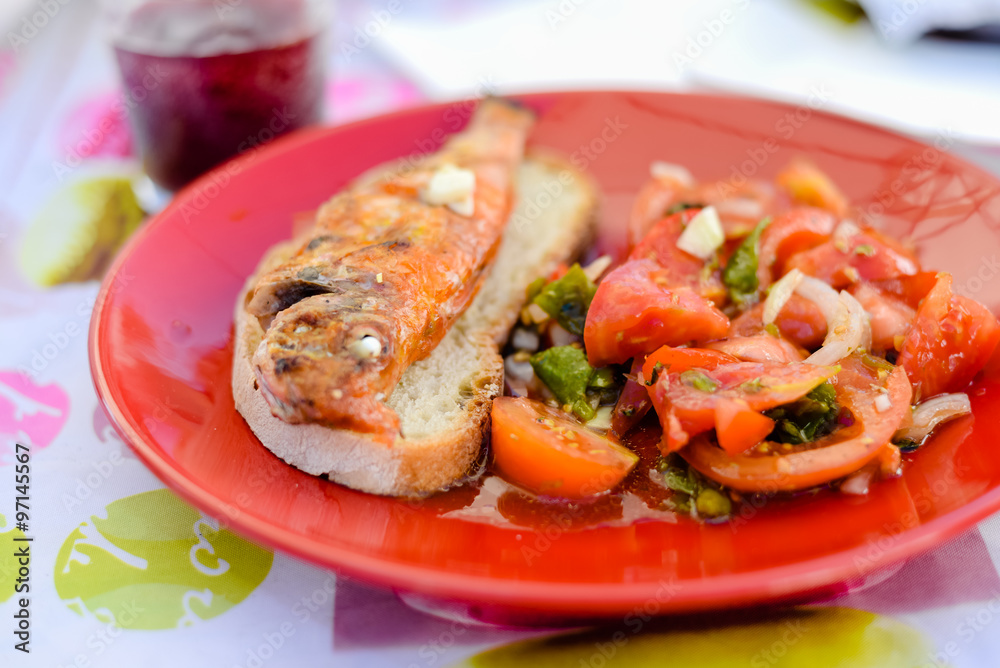 Tasty fish sandwich and vegetable salad served on red plate 