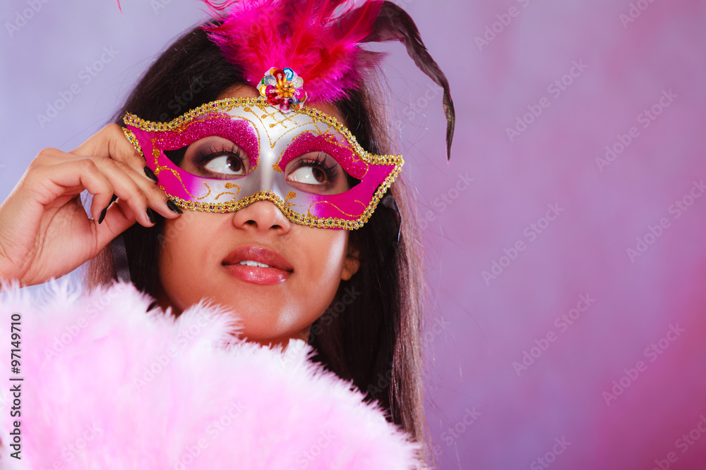 woman with carnival mask holds fan