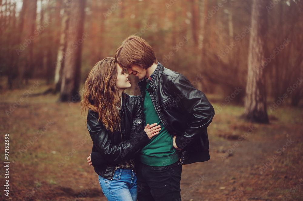 young happy loving couple in leather jackets hugs outdoor on cozy walk in forest young happy loving couple in leather jackets hugs outdoor on cozy walk in forest