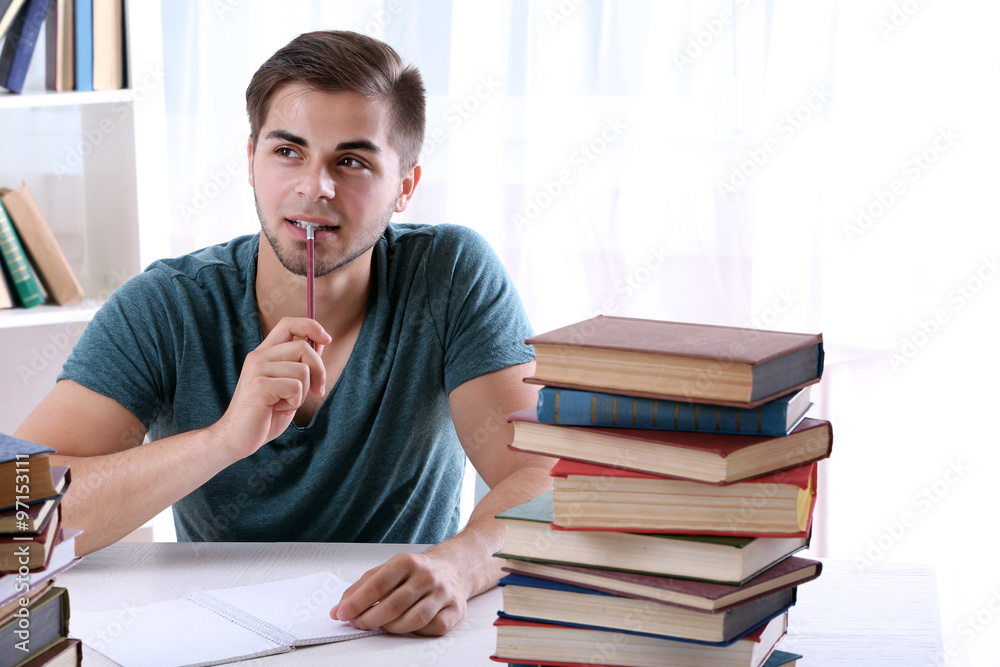 Young man reading book at table in room Young man reading book at table in room