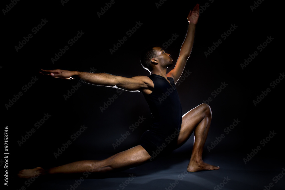Fototapeta premium Black male dancer practicing warm up exercises for flexibility