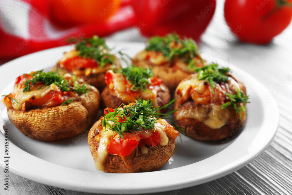 A plate with stuffed mushrooms on wooden background