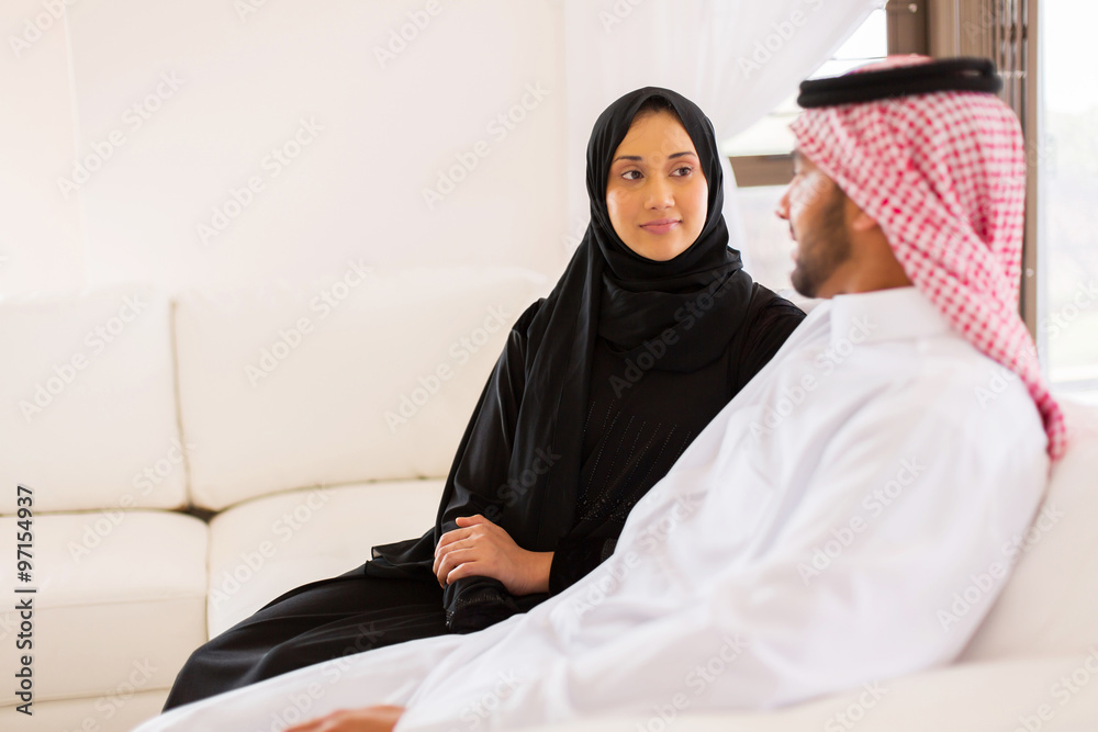 young muslim couple sitting on sofa
