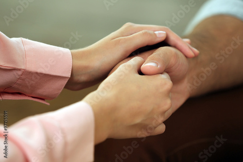 Concept of support - man and woman holding hands in the light room