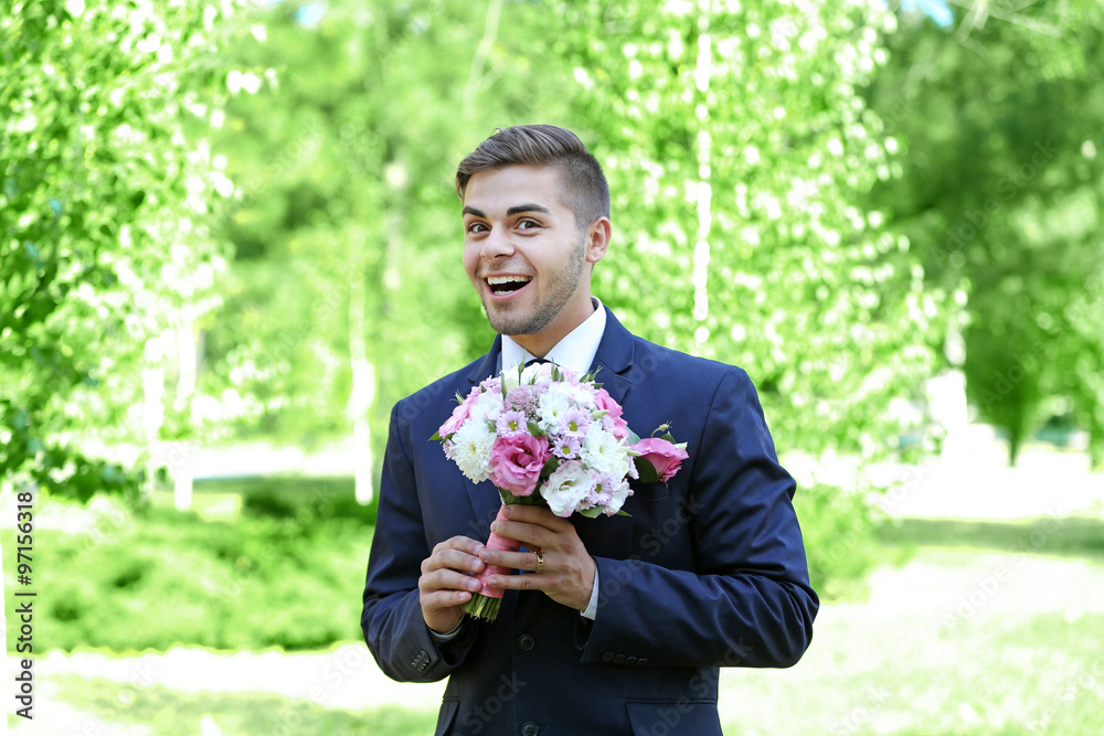 Groom holding wedding bouquet outdoors Groom holding wedding bouquet outdoors