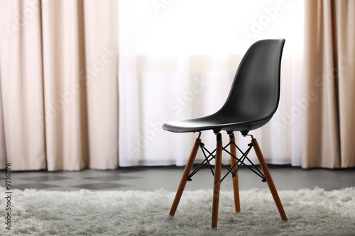 Stylish conception with black chair on light room background