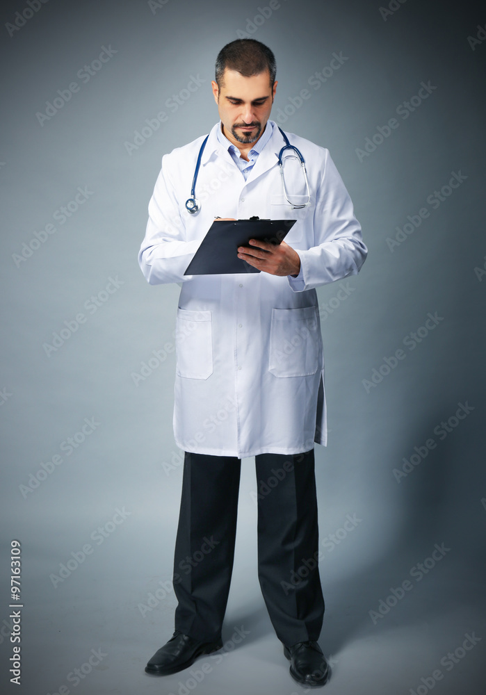 Portrait of a doctor with prescription board in hands on grey background Portrait of a doctor with prescription board in hands on grey background