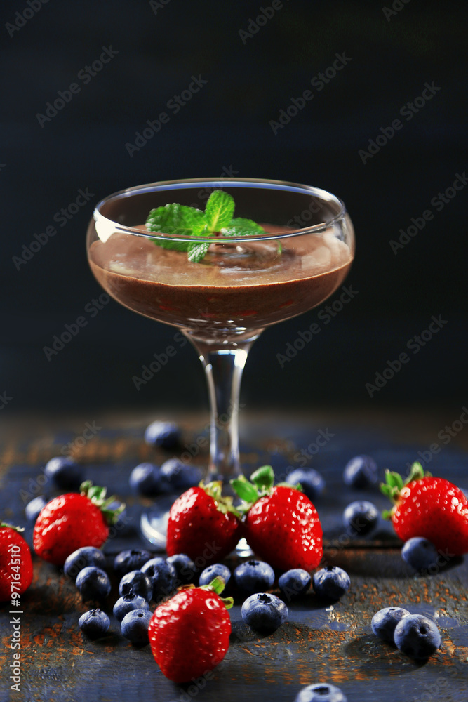Chocolate dessert in glass and fresh berries on color wooden background Chocolate dessert in glass and fresh berries on color wooden background