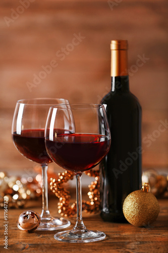 Red wine and Christmas ornaments on wooden table on wooden background