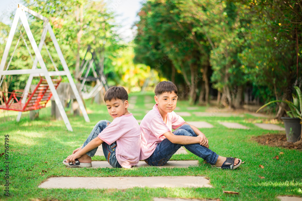 Little sibling boy sitting together in the park