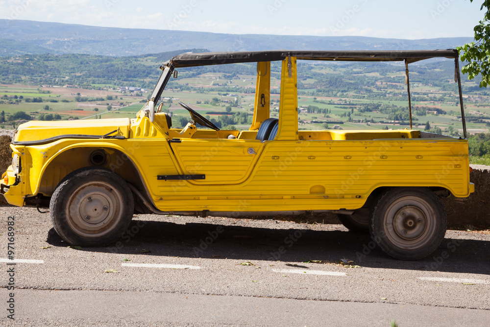 Vintage yellow crossover vehicle in the street of a small european town