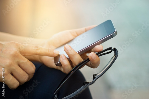 Close up of a woman using mobile smart phone outdoor and glasses