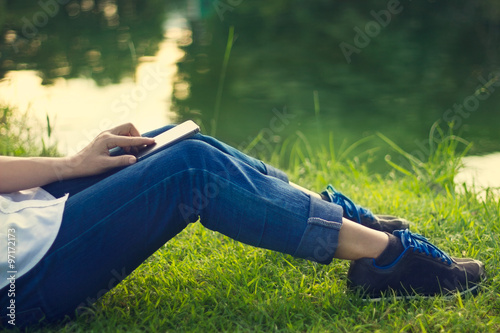 Woman using mobile smart phone on the legs, relaxing in the park