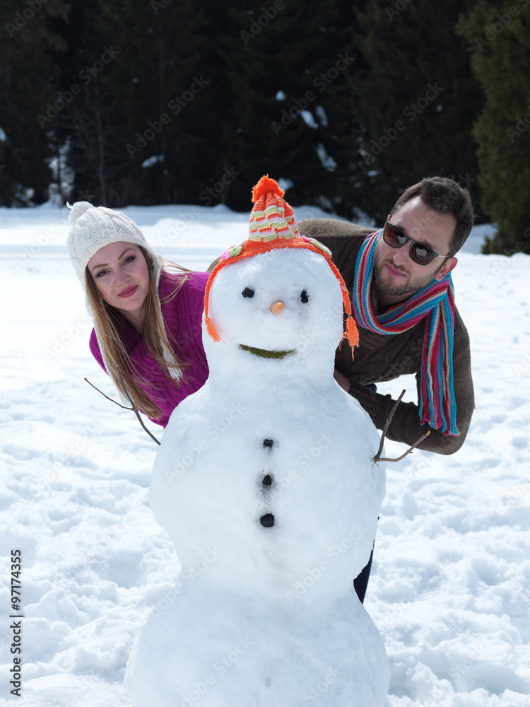 Plakat portrait of happy young couple with snowman