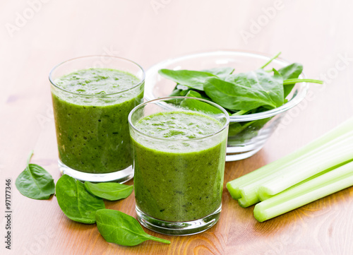 Two glass of green smoothie with spinach and celery on wooden surface
