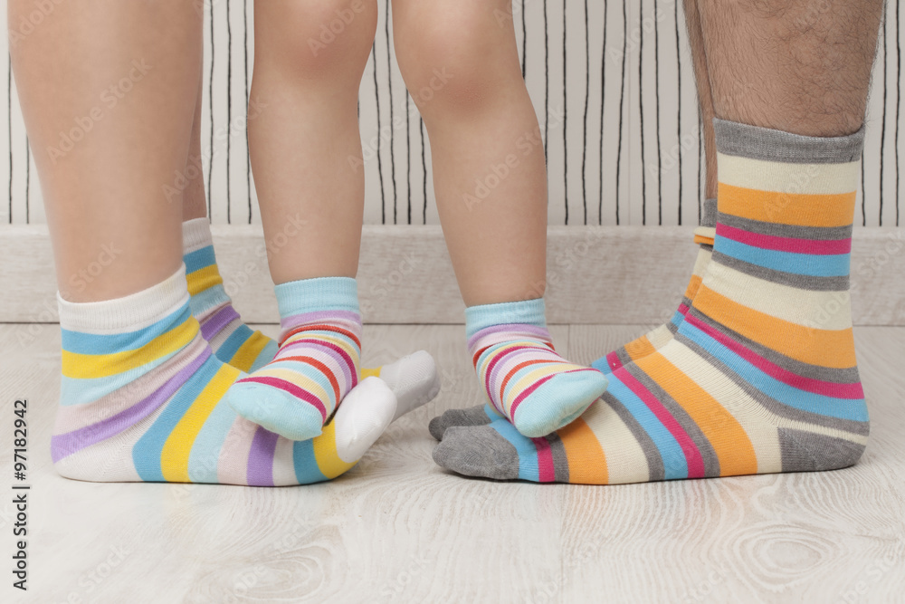 Mother, father and child wearing similar striped socks. Unrecognizable Mother, father and child wearing similar striped socks. Unrecognizable