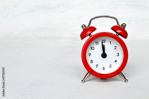 Red vintage alarm clock striking midnight or midday