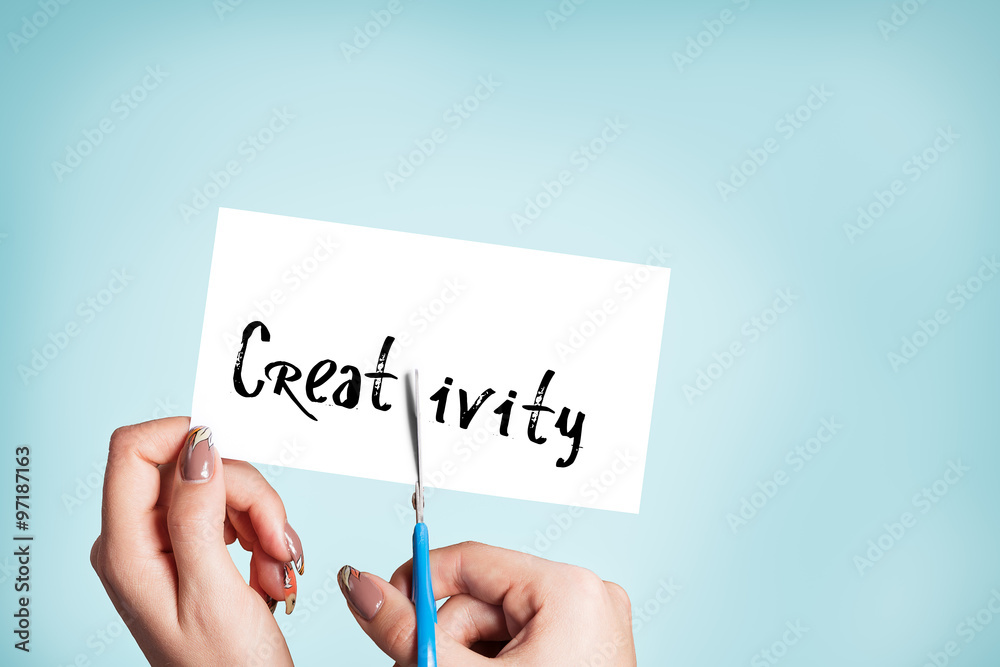 Woman hands cutting card with the word creativity Woman hands cutting card with the word creativity