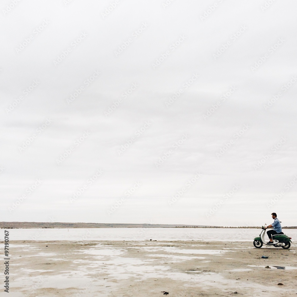 hipster man silhouette  drive on motocycle on the sea beach