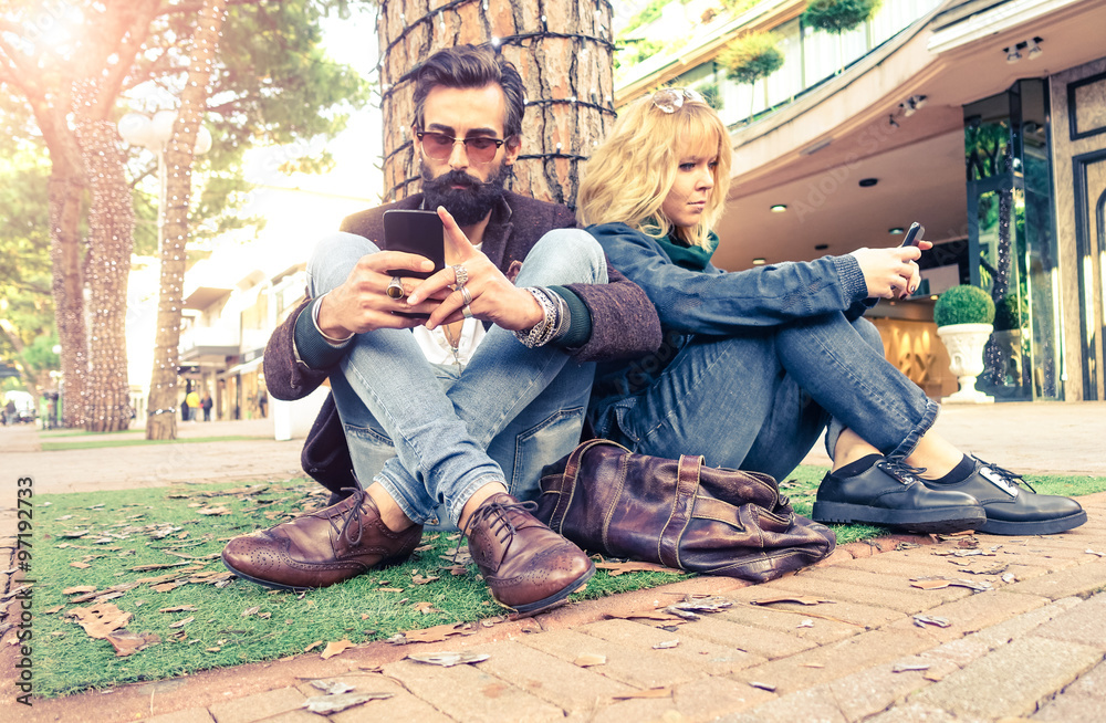 Couple holding smart phone with serious facial expression - Bearded man with mobile sitting near woman on the street - Concept of addiction to modern technology - Focus on male hands and telephone