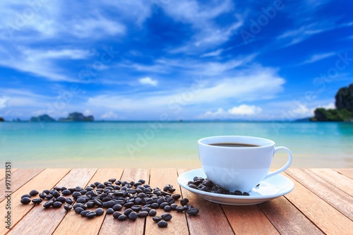 White coffee cup and coffee beans on wood table and view of suns