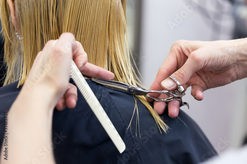 A hairdresser making haircut for a blonde female client