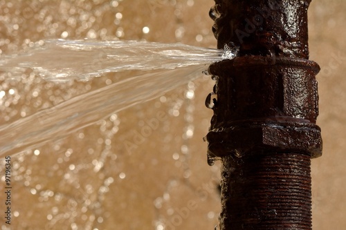 Fotografia Rusty burst pipe squirting water at high pressure