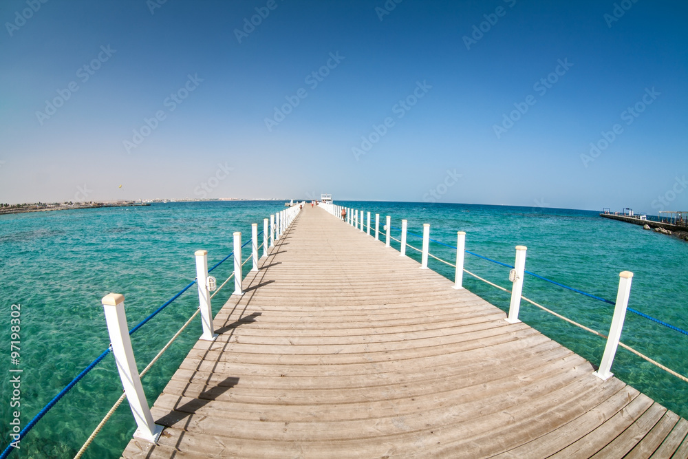 Wooden pier going far to the Red Sea at the sunny weather, turquoise water, fisheye lens