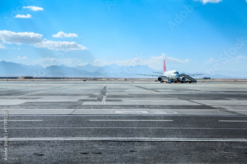 Airport runway and airfield with airliner standing under maintenance, copy space