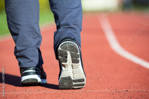 Athlete's foot close-up in running shoes stand on a stadium line