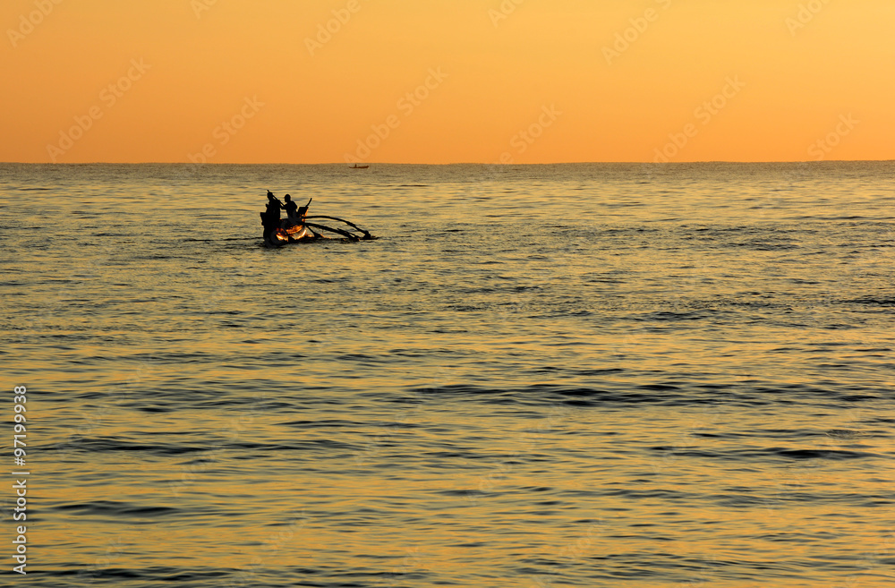 Wild beautiful beaches of Sri Lanka. Golden tropical sunset. Silhouette of  fishermen on the horizon.