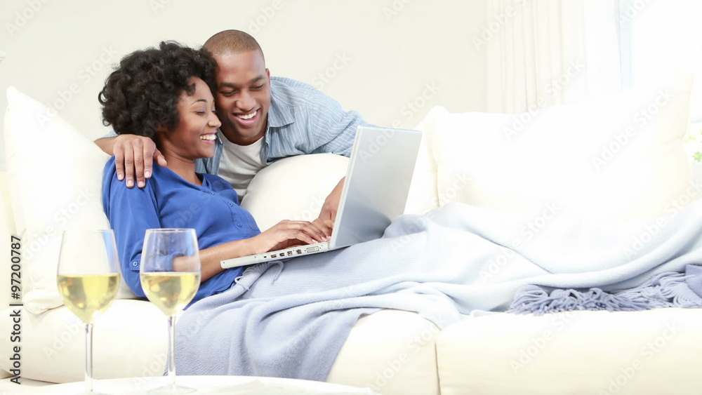 Attractive couple using laptop on the couch Attractive couple using laptop on the couch
