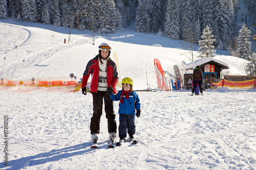 Beautiful young mom and her toddler boy, skiing in the mountains