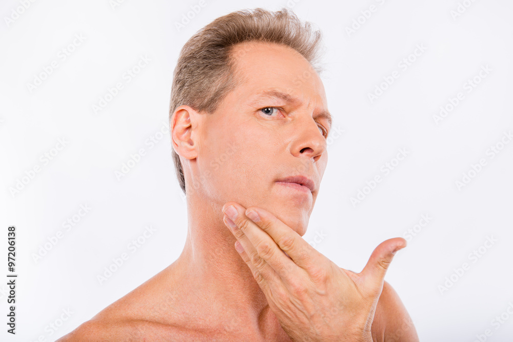 Handsome disturbed aged man touching his face after shave Handsome disturbed aged man touching his face after shave