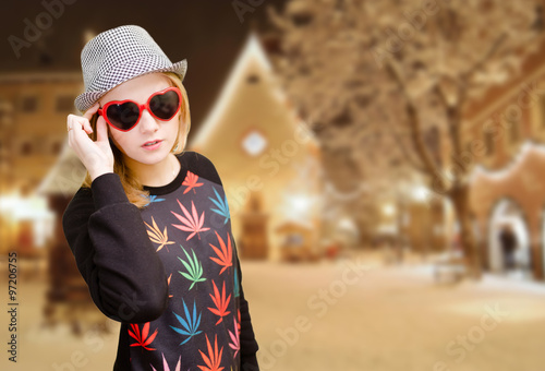 Smiling girl in dotted hat wearing sunglasses on winter background