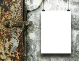 Single hanged vertical paper sheet frame on the right with clips on rough concrete wall background with rusty door handle nearby