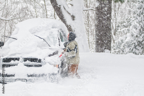 man clearing snow off his truck during a winter blizzard