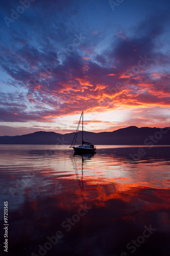 Colorful sunrise above boat at lake Attersee, Salzkammergut, Upper Austria