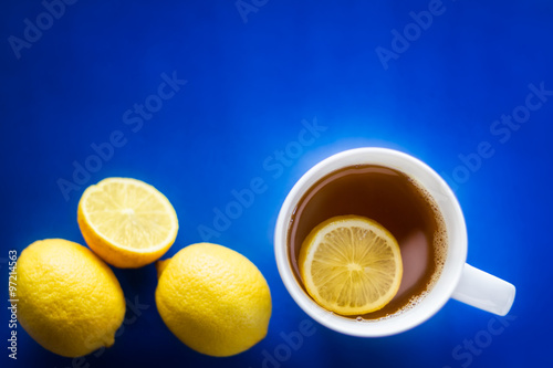 Cup of green tea with lemon on blue blackground