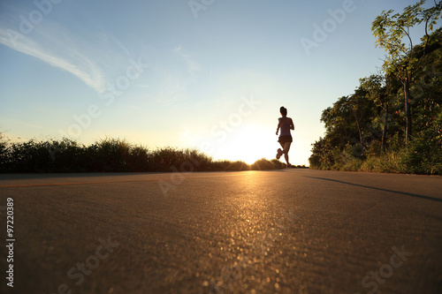 young fitness woman running on sunrise seaside trail © lzf