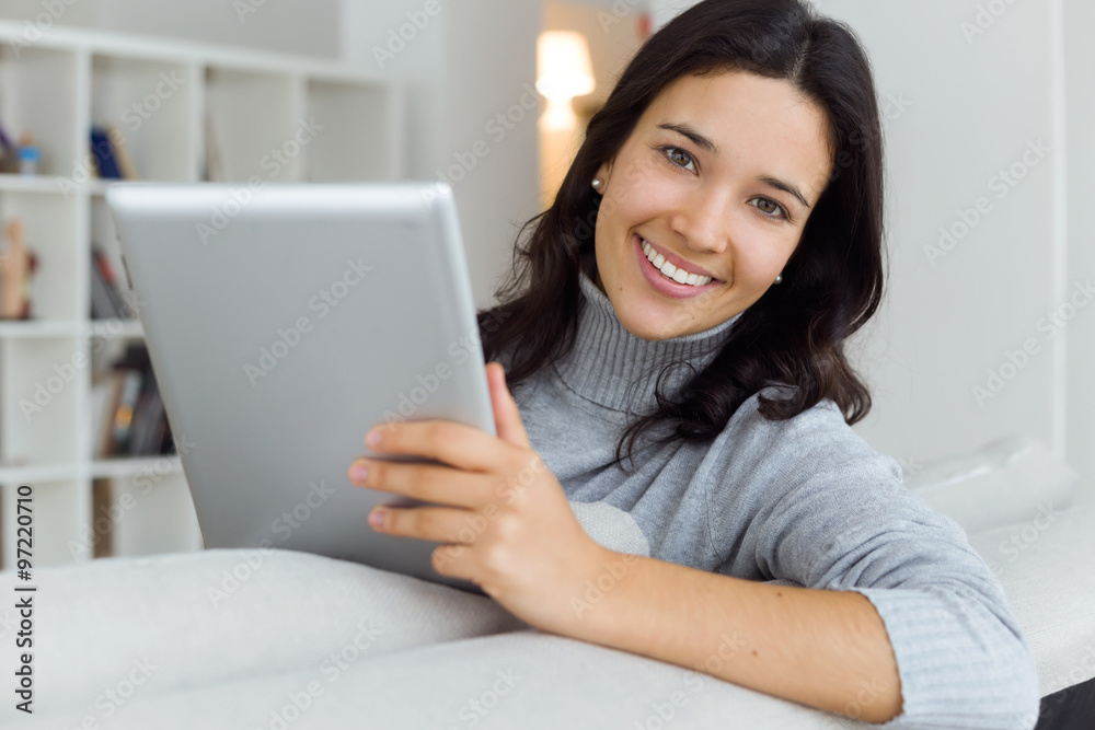 Beautiful young woman using her digital tablet at home. Beautiful young woman using her digital tablet at home.