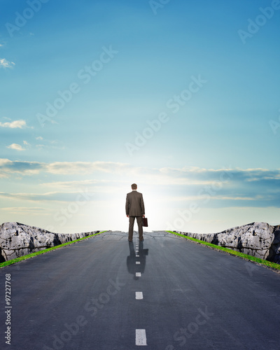 Businessman in suit walking on road with mountains