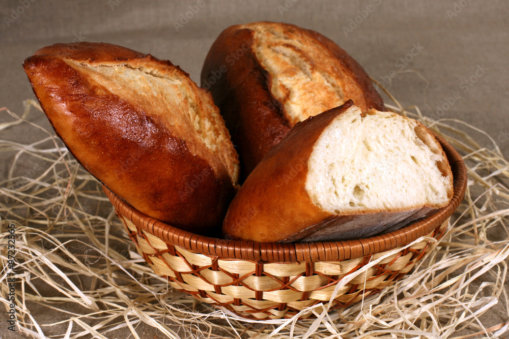  white bread is in a straw basket on the tablecloth gray linen