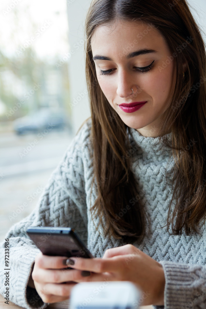 Beautiful young woman using her mobile phone in coffee. Beautiful young woman using her mobile phone in coffee.