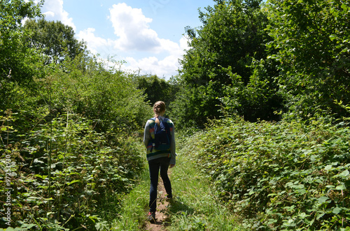 Girl walking on small path through forest