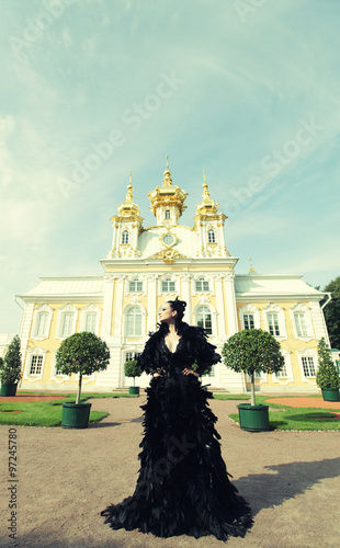 Beautiful woman in black dress posing next to the palace.