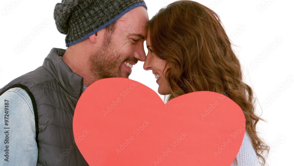 Young couple covering their face with a pillow heart Young couple covering their face with a pillow heart