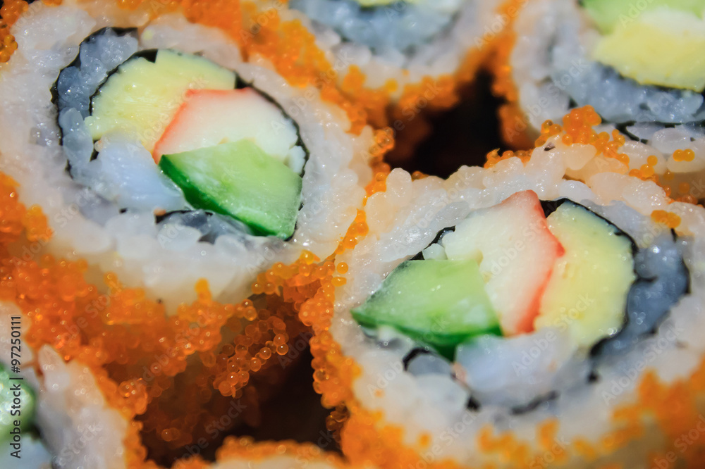 Sushi roll, row of California maki roll sushi with caviar on bla Sushi roll, row of California maki roll sushi with caviar on bla